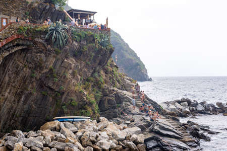 VERNAZZA, ITALY - JUNE 26, 2017: Tourist walking on stairs and sitting on rocks looking at sea.のeditorial素材