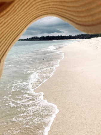 Beautiful daylight view from beach line to blue sea and waves, white sands. Grand Port District, Mauritius island, composition with woman hatの写真素材