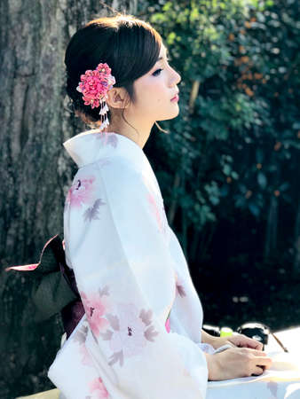 TOKYO, JAPAN - OCTOBER 9, 2017: Daylight portrait of dark hair asian female dressed in traditional clothes kimono with sakura ornaments and flowersのeditorial素材