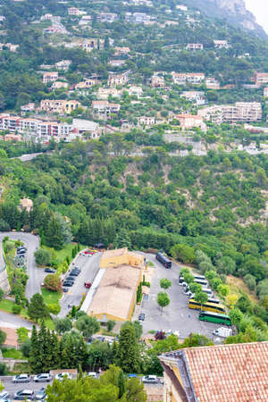 Daylight foggy view to Eze, France Cote d'Azur village with medieval houses, roads and green trees...