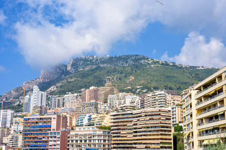 Daylight sunny view to city big buildings and mountains full of trees. Bright blue sky with a few...