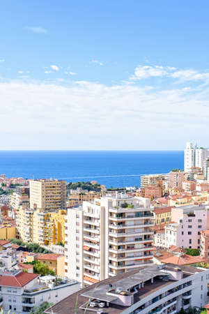 Daylight view to tall city buildings and blue sea with boat traces on water. Bright blue sky with clouds. Negative copy space, place for text. Monte Carlo, Monacoの写真素材