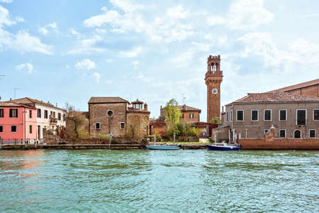 Daylight view to Venetian Lagoon and parked boats. Sidewalk with colorful historic architecture...