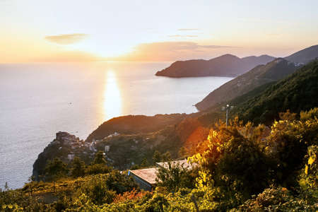 Sunset visible from a hill, light reflected in the water of Mediterranean sea in Cinque Terre, Italyの写真素材