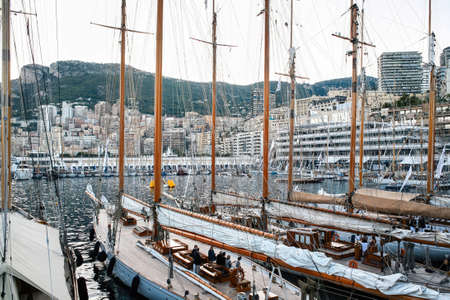Moored old ships in Monaco with people on the board, yachts and buildings on the background