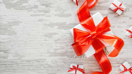 Multiple white gift boxes with red tapes on wooden background. Top viewの写真素材