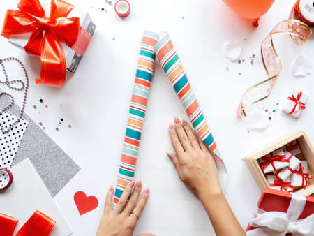 Female hands on table with things for preparing gifts, gift boxes, tapes, stationery. Holiday concept. Top viewの写真素材
