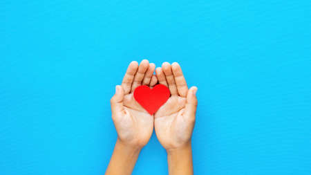 Man hands holds a red heart on blue background. Love concept. Top viewの写真素材