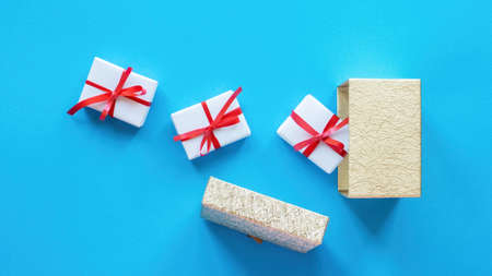 White gift boxes with red tapes and opened box on blue background. Top view