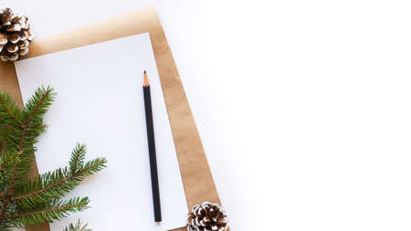Notebook with a pencil, fir cones, Christmas tree branch. White background. Holiday concept. Top...