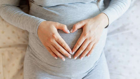 Pregnant woman lying on the bed and holding her belly