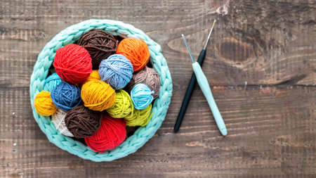 Multicolored balls of yarn in the knitted couch with knitting equipment. Top viewの写真素材
