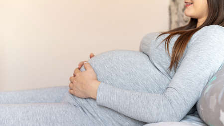 Pregnant woman lying on the bed and holding her belly