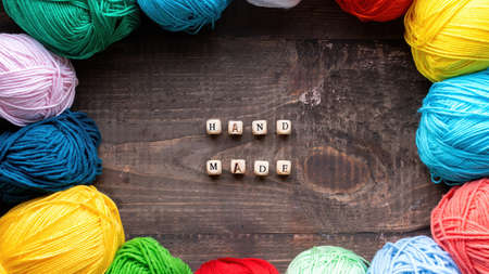 Multiple colored balls of yarn with wooden letters composing words hand made. Top viewの写真素材