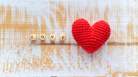 Handmade knitted red heart with wooden letters composing word love. Top view