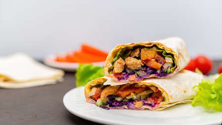 Healthy food composition. Vegetables and cutted in a half a pita roll on dishesの写真素材