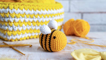 Knitted yellow bee toy with knitting equipment on the tableの写真素材