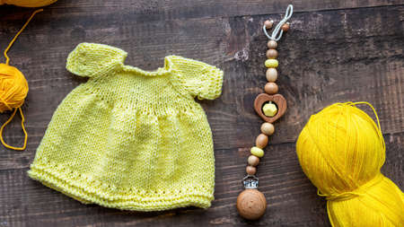 Knitted yellow small dress with knitting equipment and decoration on the tableの写真素材
