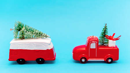Two red and white toy cars with christmas trees on it. Blue background