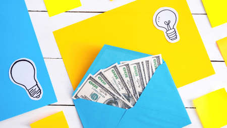 Blue envelope with money with yellow and blue papers, icons of lampの写真素材