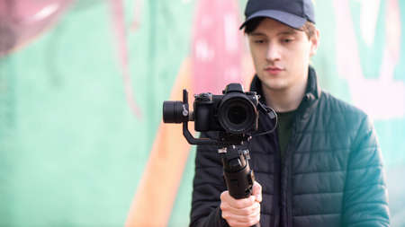 Man holding a camera on steadycam, colored background