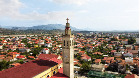 Aerial drone view of Tirana, Albania. Residential district with a church and multiple buildings, mountains in the distanceの写真素材