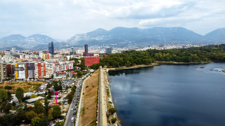 Aerial drone view of Tirana, Albania. City centre with modern buildings, residential district and greenery, lake, mountains in the distanceの写真素材