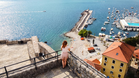 Aerial drone view of a woman in a fortress in Montenegro. Fortress located on the Adriatic coast, boats and pierの写真素材