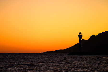 Dark orange red sunset with lighthouse and mountains in Cannes, Franceの写真素材