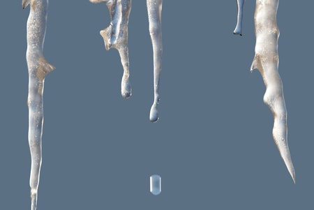 Melting icicles and a detached drop isolated on blue backgroundの写真素材