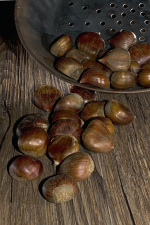roasting chestnut in a typical italian pan on wooden tableの写真素材