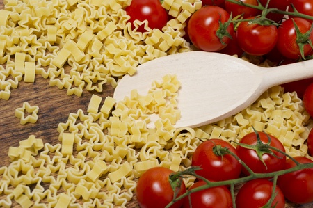 italian pasta and little tomatoes on wooden tableの写真素材