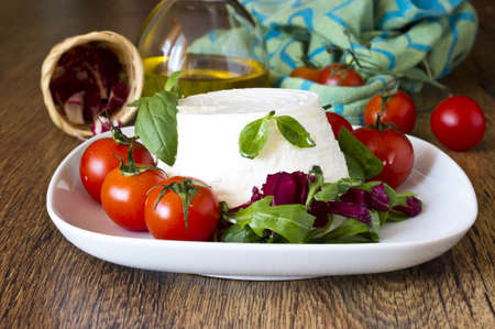 italian fresh ricotta with tomatoes and salad on wooden tableの写真素材