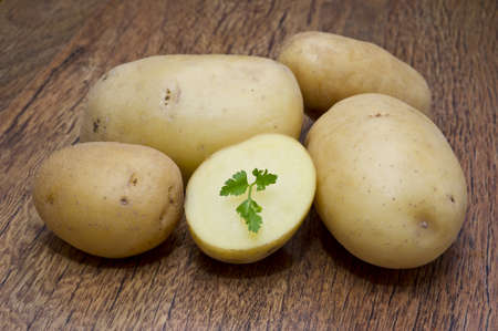 potato and parsley leaves on wooden tableの写真素材