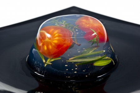 Homemade aspic with tomatoes and rosemary on black plateの写真素材