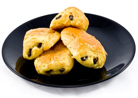 Fresh and tasty buns with raisins over black plate