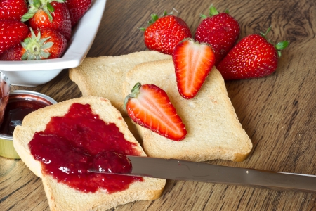strawberries jam and rusk on wooden table with a knifeの写真素材