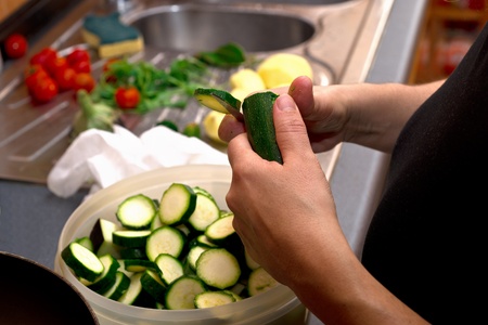 Close up of woman in home  kitchen working; she is preparing vegetables