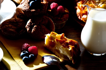 Homemade muffins with milk and  apple pie on wooden table  ready for breakfast in early morning lightの写真素材