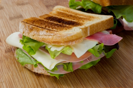 sandwich with salad, cheese and ham on wooden tableの写真素材