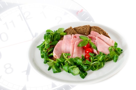 A white plate with ham and salad on clockの写真素材