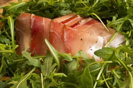 european ham called speck on wooden board with green salad の写真素材