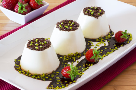 Italian dessert called "panna cotta" with strawberries on wooden tableの写真素材