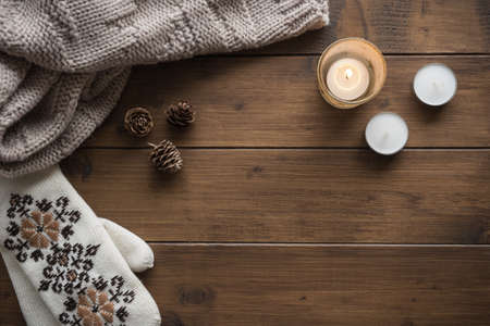 Christmas or winter background with a scarf, mittens, candles and fir cones, top viewの写真素材