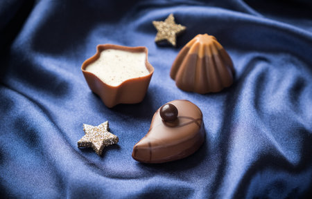 Delicious chocolate pralines with stars on the blue silk background, close upの写真素材