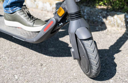 An electric scooter with a man foot, close up of the front wheel