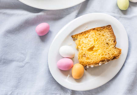 Piece of traditional italian Easter cake Colomba and Easter marzipan eggs in pastel colors, top view