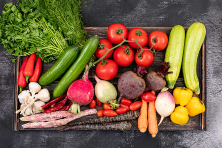 Different vegetables on wooden board, top view on black background