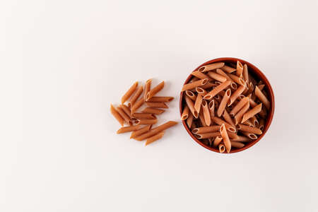 Brown raw pasta in bowl top view on white backgroundの写真素材