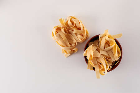 Raw tagliatelle pasta in the bowl top view on white backgroundの写真素材